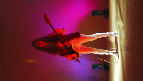 Vertical-video-of-a-woman-playing-a-guitar-but-changing-background-light-and-strobe-lights-of-a-concert-light